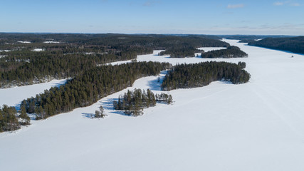 Fototapeta na wymiar Aerial view of beautiful winter lake and forest in National park in Fnland. Winter scenery from above. Landscape photo captured with drone.
