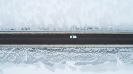Aerial view of a snowy bridge as car drive across it
