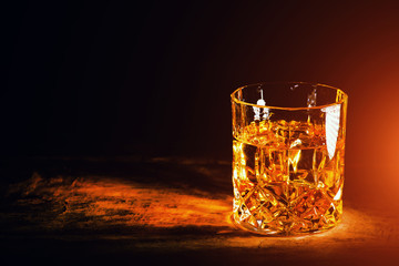 whiskey with ice cubes on wooden background