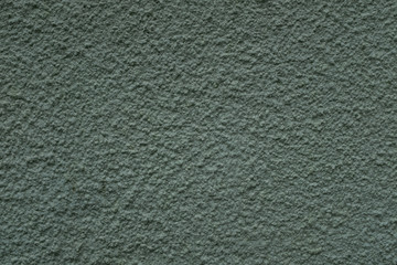 A close up photo of an exterior wall painted green textured, surface with stucco daub, great for background