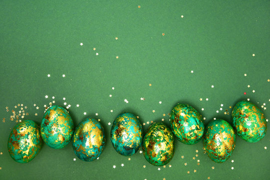 Easter eggs, dark green with gold on a green background. View from above. Flat lay.