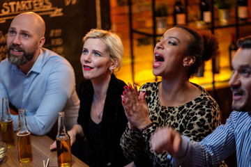 Group of friends watching tv in a cafe behind bar counter