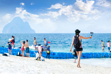 Young woman travel blogger works with smartphone on the tropical beach. Travel concept.