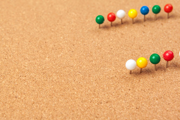 Group of thumbtacks pinned on corkboard
