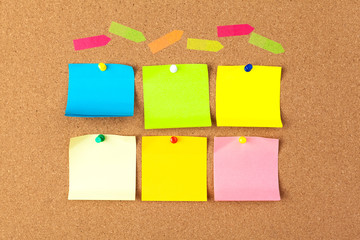 Cork board with several colorful blank notes with pins