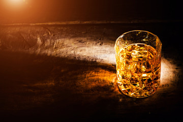 whiskey with ice cubes on wooden background