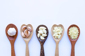 Garlic on wooden spoon on white