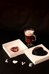 hot drink in a glass cup with pink marshmallows and white box with a transparent cover in the form of heart with cookies