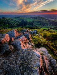 purple sunset on top of milseburg in Germany with stones and rocks in the foreground