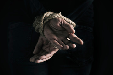 man with his hands tied behind his back