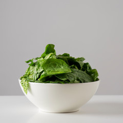 raw spinach leaves in a white bowl.
