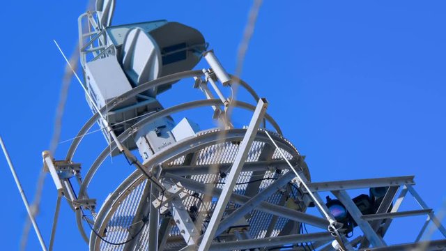 Weather radar with a rotating radiodetection antenna on top of a mountain collects weather data from whole around area