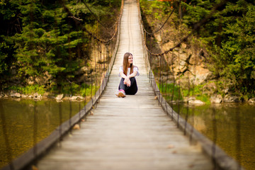 Tourist woman walk by long wooden suspension bridge above river.