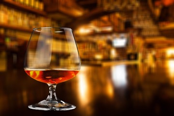 Glass of whiskey and Ice on wooden table on blurred background
