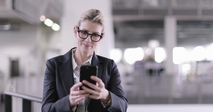 Senior female business executive using smartphone in a corporate office