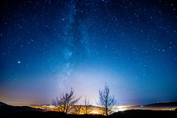 Long exposure photograph of the Milky Way and its galactic center on a forest near the city of...
