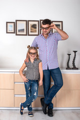 Studio shot of a daughter and dad standing  in the room in identical points the same way.  Daughter...
