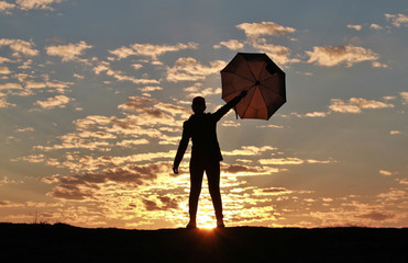 Silhouette girl with umbrella on the background of incredible sunset, sky and clouds