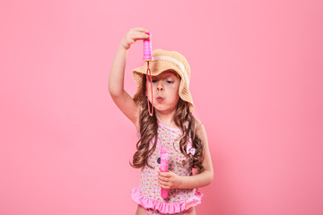 little girl blowing soap bubbles on colored background