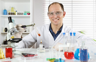 Happy young scientist conducting research in a chemical laboratory