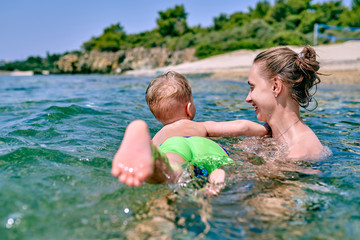 Fototapeta na wymiar Toddler boy learns to swim with mother