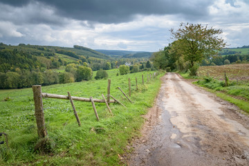 Fototapeta na wymiar Bad road between agricultural fields in the Belgium Ardennes