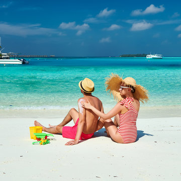Woman applying sun screen lotion on man's back