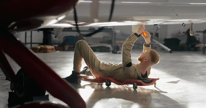 Portrait of aviation maintenance worker lying under aircraft wing