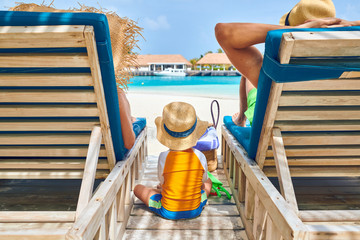 Family at beach on wooden sun bed loungers