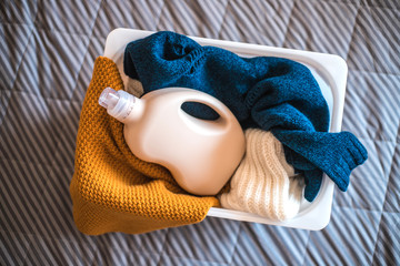 Bottle of detergent with sweaters in container.