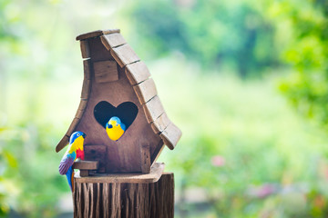 Bird house heart-shaped entrance and two love birds in the garden