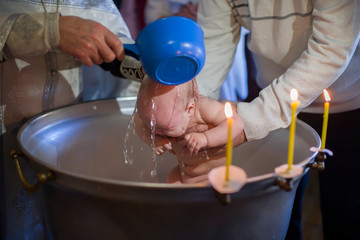 Priest pours water on the infant at baptism. Orthodox rite of baptism. Acceptance of faith. Child in the font