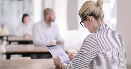 Businesswoman in a café using a digital tablet - Powered by Adobe