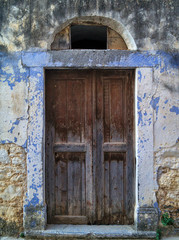 Rustic old wooden door on colorful wall in a village in Chios island, Greece.