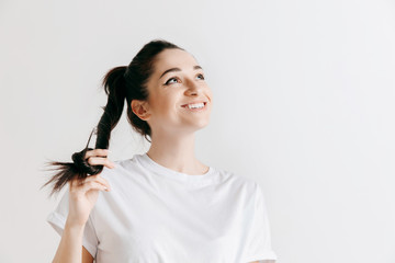 Happy woman standing and smiling isolated on gray studio background. Beautiful female half-length portrait. Young emotional woman. The human emotions, facial expression concept.