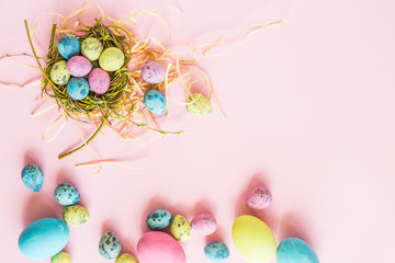 Painted easter eggs, floral branches, nest lying on pink background