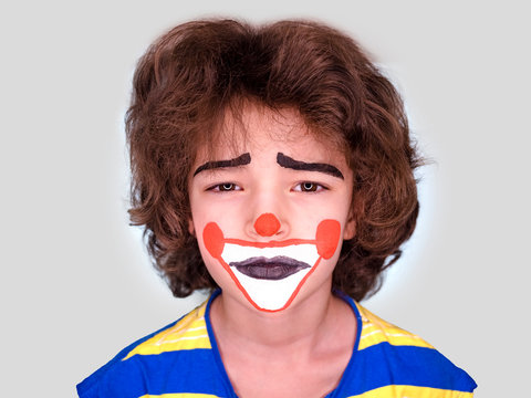 little cute boy with facepaint like clown, pantomimic expression. April Fool's Day, April 1. Isolated on gray