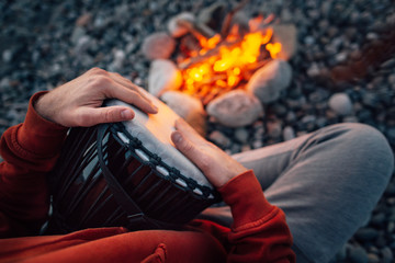 percussionist playing djembe sitting by fire, close-up