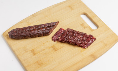 Pieces of sausage made from horse meat on a chopping Board.