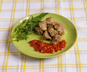 Pieces of roast meat, tomato sauce, dill bread and fried cabbage on a plate on a napkin.