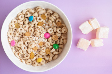 Corn Flakes and oatmeal, in a white bowl on the violet background. 