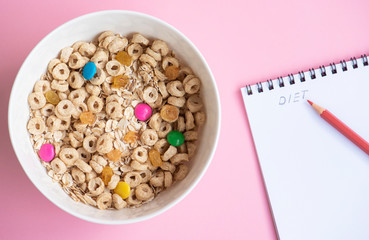 Cornflakes and oatmeal, in a white bowl, notepad and pencils. Diet concept. 