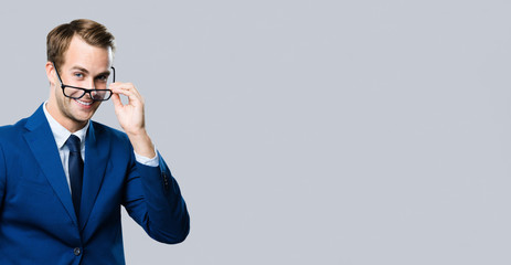 young businessman in glasses, against grey