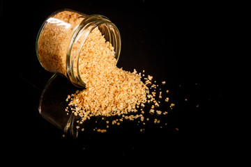 big yellow organic sea salt poured out from small glass jar