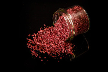 big burgundy organic sea salt poured out from small glass jar