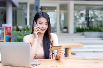 Asian woman callphone and holding credit card. Online shopping concept.