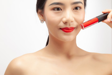 Young asian woman applying red lipstick on white background.