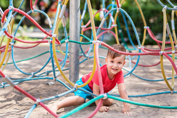 little boy playing in the rope net on the playground
