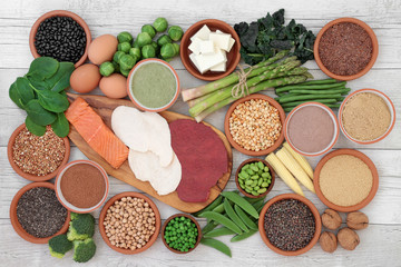 High protein food sampler with fresh vegetables, meat, fish, tofu, legumes, nuts, supplement powders, grains and seeds. High in dietary fibre, antioxidants and vitamins. Top view.