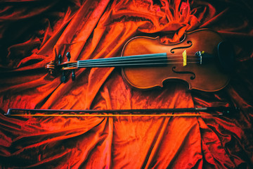 The abstract art design background of classic violin and bow  put on red cloth